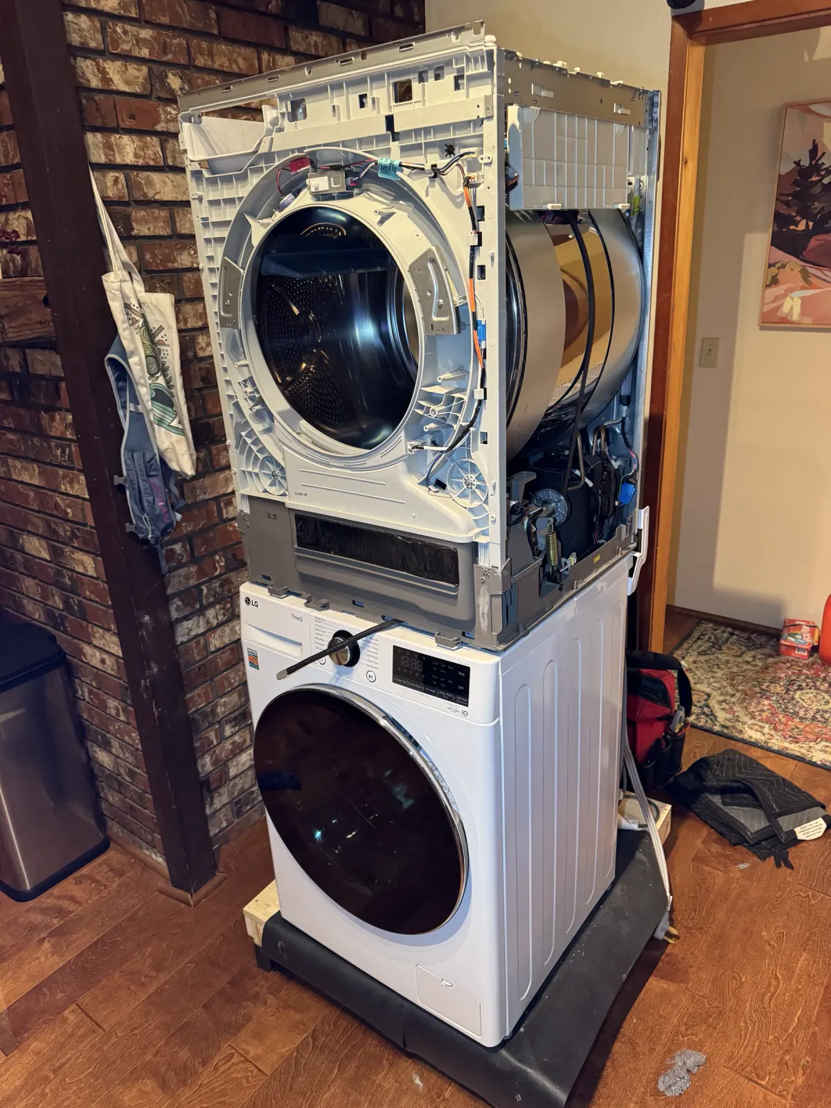 Stacked LG dryer disassembled above the washer for access to the drum, belt, motor, and heating system
