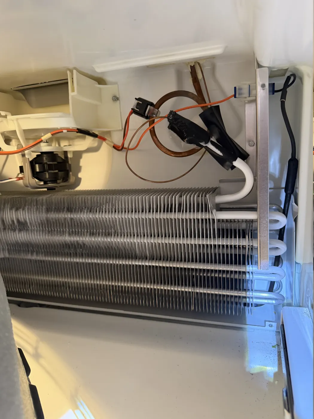 Refrigerator fan, evaporator coil, wiring, and tubing visible during diagnosis