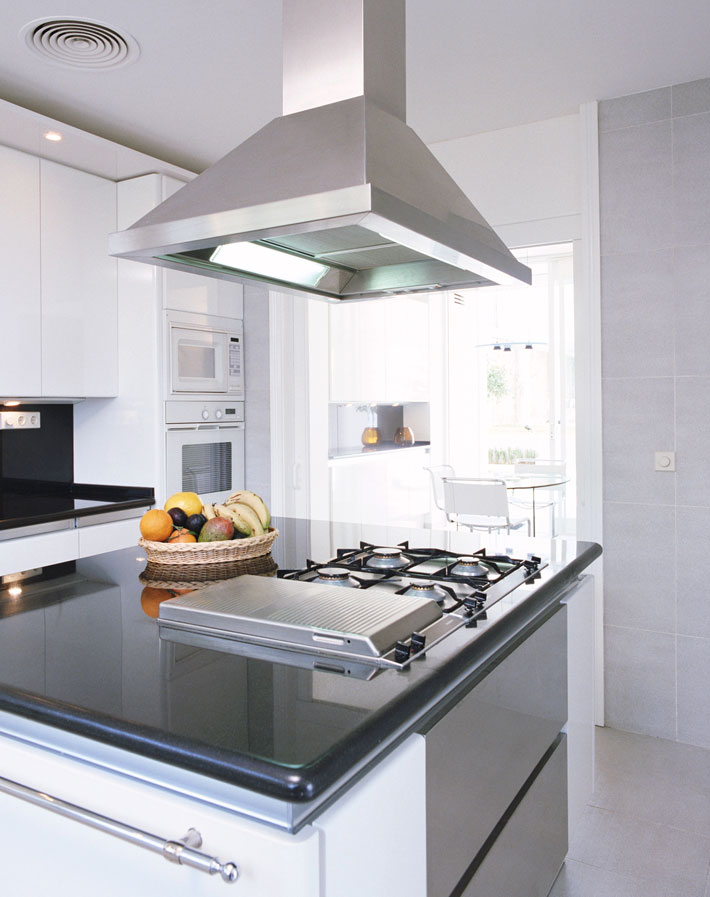 Stainless steel wall-mounted range hood above a residential cooktop